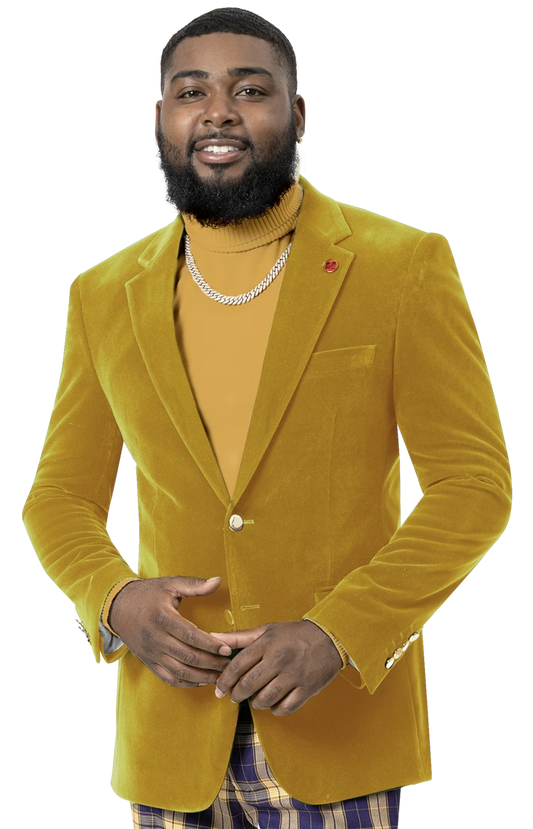 Dressed in the EJ Samuel Mustard Velvet Blazer J134 from the renowned brand EJ SAMUEL, a person wearing a turtleneck embellished with gold buttons smiles warmly, their look perfectly complemented by a stylish necklace.