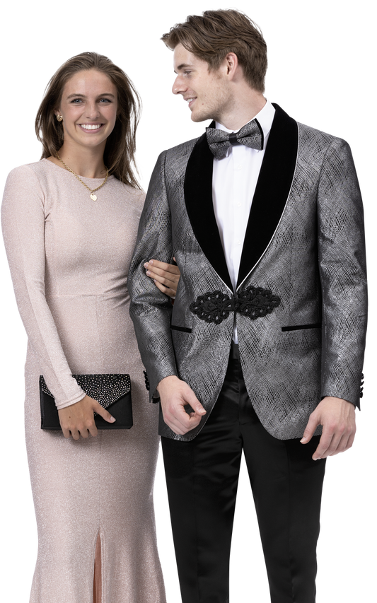 A woman in a long, light pink dress stands beside a man dressed in an EJ Samuel Pewter Blazer J173 from EJ SAMUEL, paired with a bow tie. She holds a clutch that complements their sophisticated fashion ensemble as they both smile elegantly.