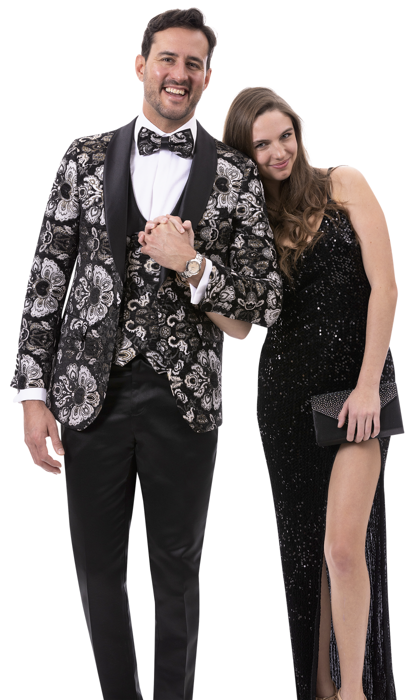 A man in the EJ Samuel Black Blazer J179, styled with a floral tuxedo and matching bow tie, stands smiling alongside a woman in a black sequined dress against a plain background.