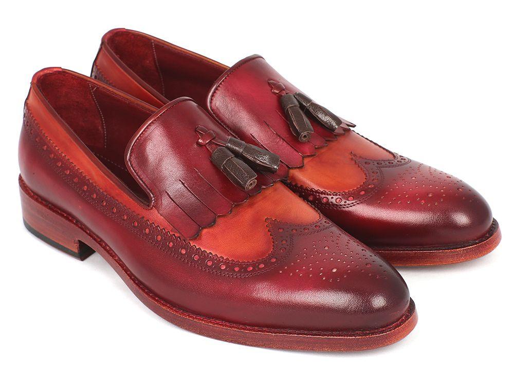 A pair of Paul Parkman Kiltie Tassel Loafers in Tobacco & Bordeaux, KT64CB, exquisitely crafted from handpainted calfskin with brown fringe details and intricate brogue patterns, arranged artfully with one shoe tilted against the other.