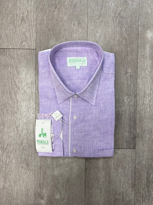 A folded Inserch Premium Linen Yarn-Dye Solid Long Sleeve Shirt in Lavender, featuring contrast trimming and tags, rests on a wooden surface.