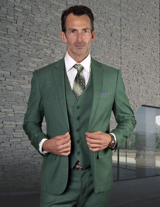 A man stands in front of a textured stone wall, dressed in the STATEMENT CLOTHING | LAZARO-FOREST suit from Statement Clothing, crafted from fine Italian fabric and accompanied by a matching tie.