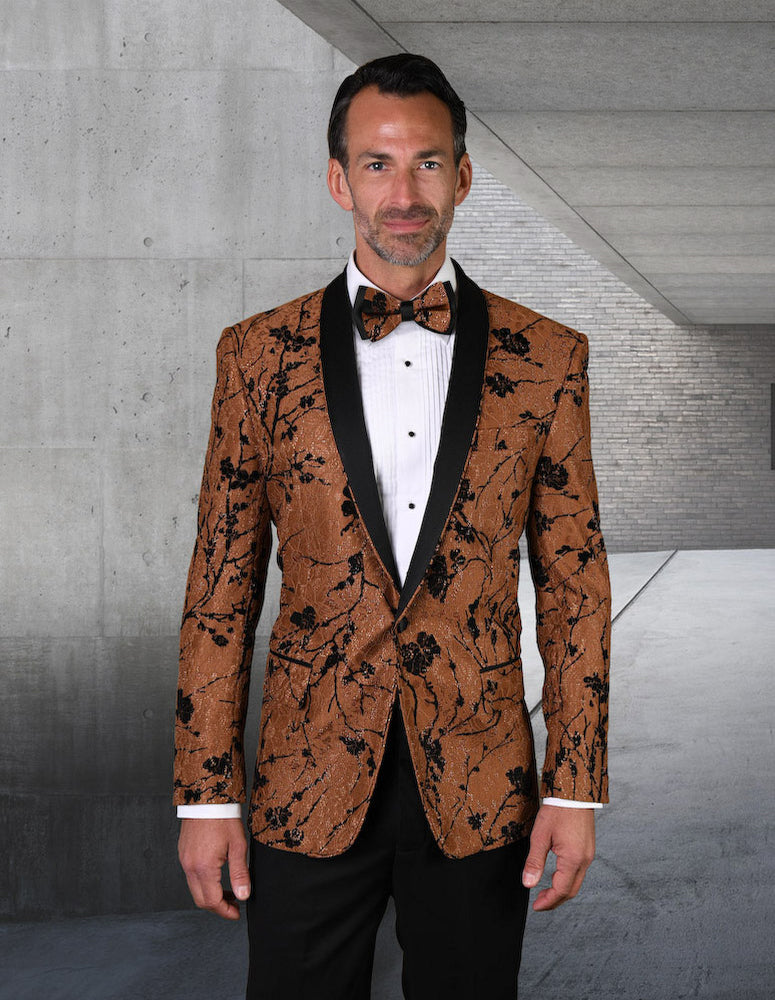 A man confidently stands in a modern, concrete interior space, wearing the STATEMENT CLOTHING | LJ-101-COPPER suit and matching bow tie from Statement Clothing.