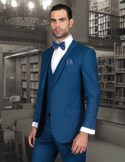 Clad in a Lorenzo-Blue slim fit suit from Statement Clothing, accented with a bow tie, the man stands elegantly in a library setting, perfectly capturing the essence of classic style.