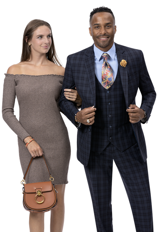 A woman in a stylish off-the-shoulder dress stands arm in arm with a man wearing the EJ Samuel Black Suit M2778, highlighting their impeccable fashion sense. She elegantly holds a brown handbag.