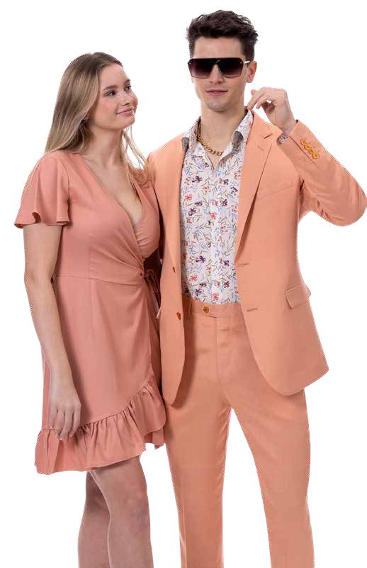 A man and woman stand together, wearing matching outfits that perfectly blend style and fabric harmony. The woman's dress flows elegantly beside the man, who complements her look with the EJ Samuel Salmon Suit M2792 paired with a floral shirt and sunglasses.