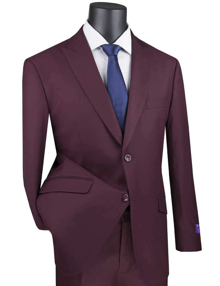 A maroon suit from Vinci Suits, featuring a modern fit and peak lapels, is showcased on a mannequin. It includes elegant side vents and is paired flawlessly with a white shirt and navy tie.