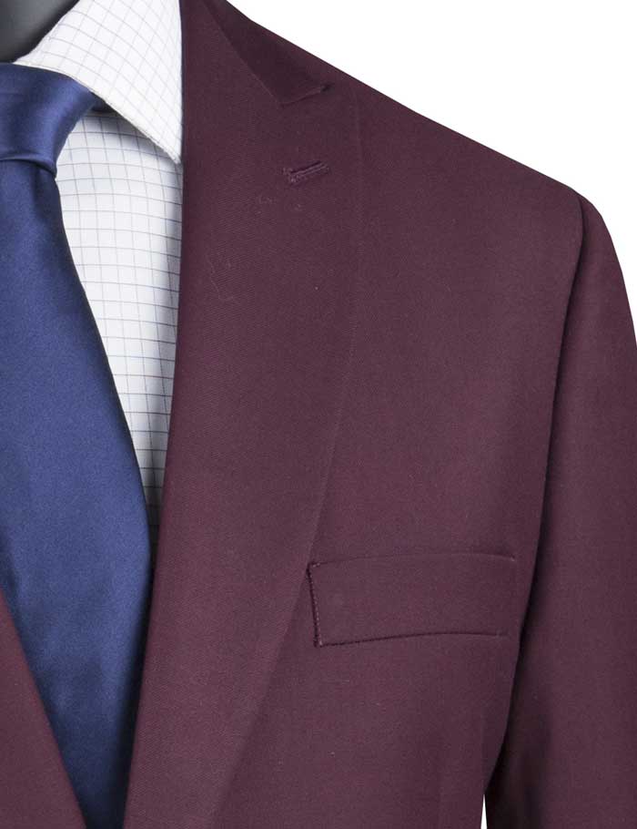 A maroon suit from Vinci Suits, featuring a modern fit and peak lapels, is showcased on a mannequin. It includes elegant side vents and is paired flawlessly with a white shirt and navy tie.