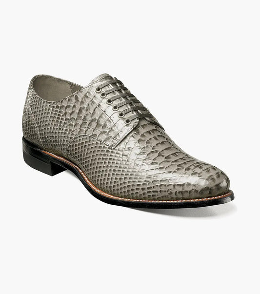 The Stacy Adams Madison Anaconda Plain Toe Oxford in gray showcases a sleek snakeskin pattern, complemented by a black leather outsole and matching laces, all elegantly displayed on a white background.