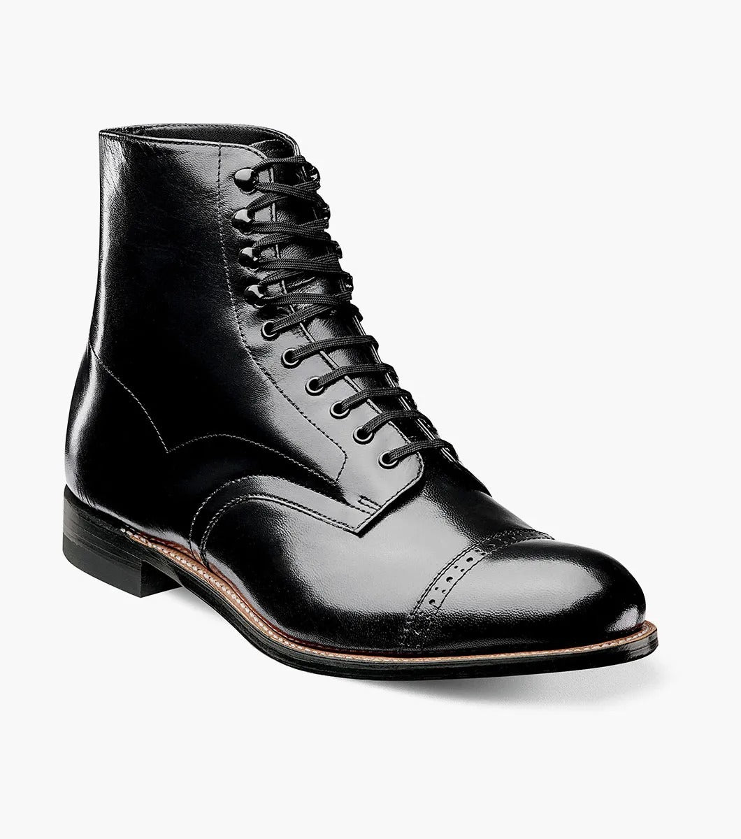 The Stacy Adams MADISON Cap Toe Boot, model 00015-01, is meticulously crafted from top-quality kidskin leather. It features a refined cap toe and a stacked heel. The durable Goodyear welt construction enhances the longevity of this sophisticated black leather boot with laces, attractively set against a white background.