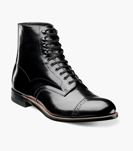 The Stacy Adams MADISON Cap Toe Boot, model 00015-01, is meticulously crafted from top-quality kidskin leather. It features a refined cap toe and a stacked heel. The durable Goodyear welt construction enhances the longevity of this sophisticated black leather boot with laces, attractively set against a white background.