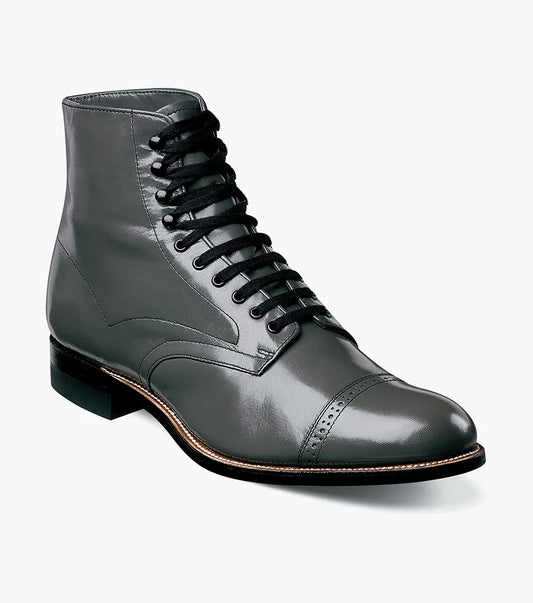 The Stacy Adams MADISON Cap Toe Boot in Steel Gray, made from high-quality kidskin leather, showcases a sophisticated lace-up design and a polished cap toe, enhanced by a sturdy black sole set against a crisp white backdrop.