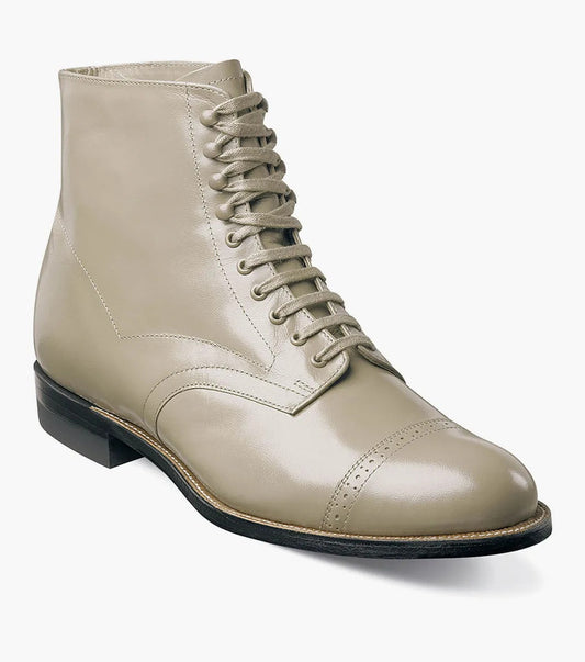 The Stacy Adams MADISON Cap Toe Boot in Taupe, crafted from luxurious kidskin leather, is a beige ankle boot with laces, showcasing a cap toe and low heel, viewed from a slight angle.