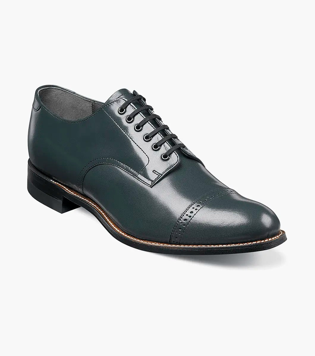 Explore the sophistication of the Stacy Adams MADISON Cap Toe Oxford in navy kidskin leather. This design includes closed lacing, a round toe, and decorative perforations. A cap toe and stacked heel complete the look against a pristine white background.