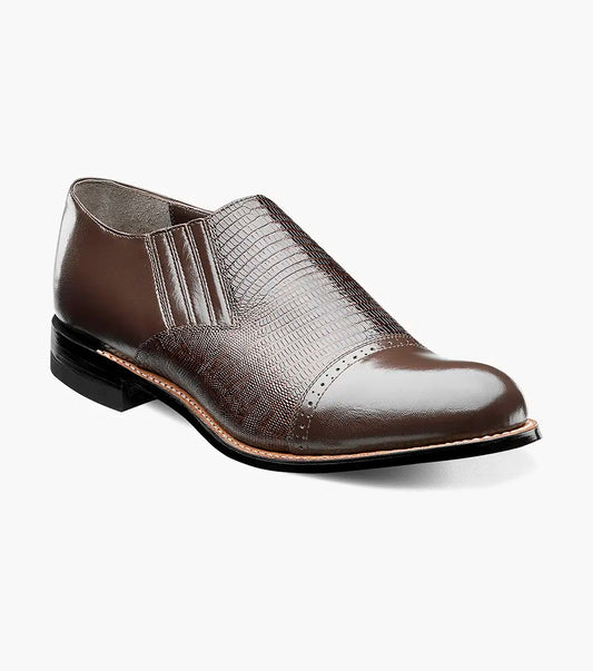 The Stacy Adams - MADISON Cap Toe Slip On in brown is shown in a side profile view against a white background. This shoe features embossed detailing and a low heel, crafted with Goodyear welt construction.