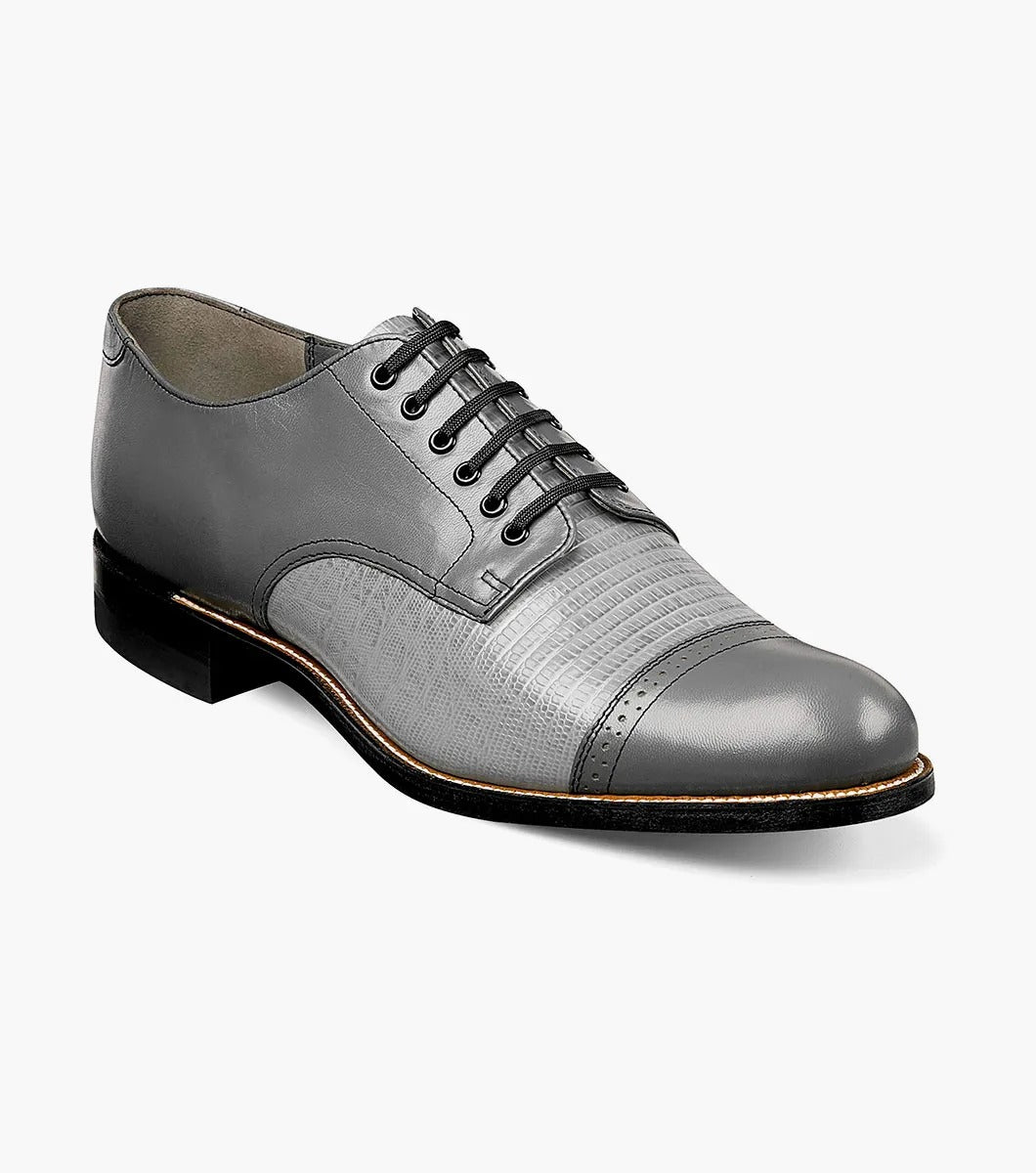 Introducing the Stacy Adams MADISON Lizard Cap Toe Oxford in Steel Gray, a sophisticated leather lace-up dress shoe from STACY ADAMS, meticulously designed with kidskin leather and featuring a detailed cap toe and a sleek black sole.