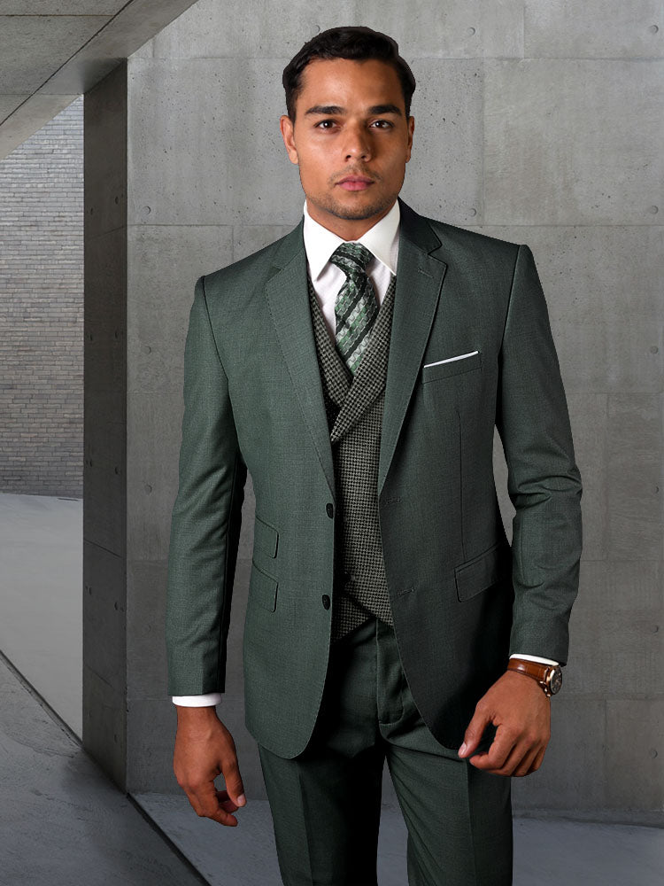 A person wearing a STATEMENT CLOTHING | MARCO-HUNTER suit in green, made from fine Italian wool by Statement Clothing, stands in a modern concrete space.