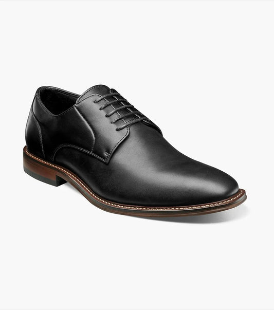 A single Stacy Adams - MARLTON Plain Toe Oxford in black leather, featuring laces, a burnished finish, brown sole, slight heel, and anatomical arch support is displayed on a plain white background.