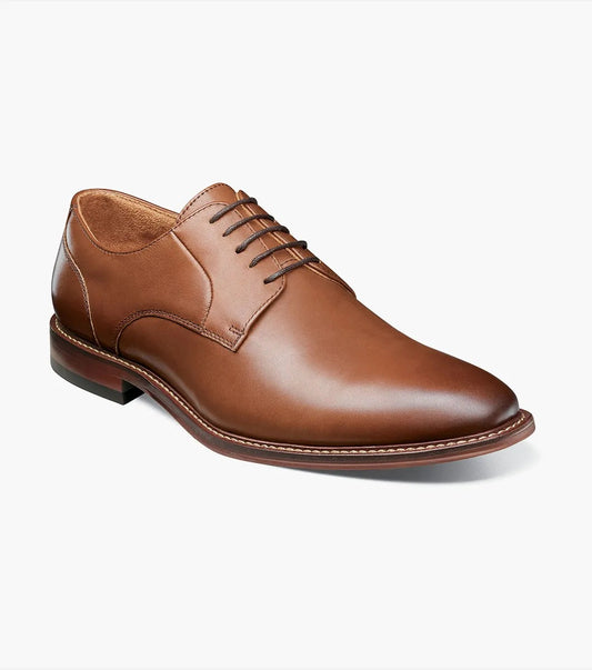 The Stacy Adams - MARLTON Plain Toe Oxford in chocolate, model 25490-202, features a brown leather dress shoe with a smooth, burnished finish and lace-up design that provides both style and comfort. The anatomical arch support offers all-day ease, set against a pristine white background.