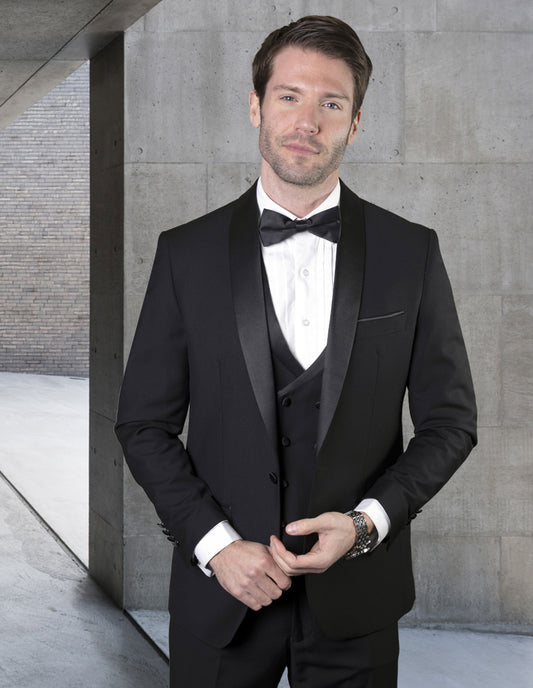 A man wearing the MGM-BLACK tuxedo suit by Statement Clothing, crafted from fine Italian fabric, stands elegantly in front of a concrete wall.