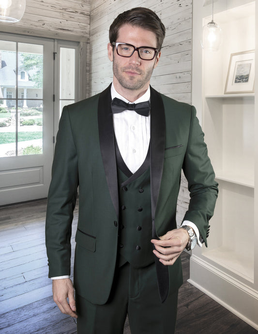 A man wearing the STATEMENT CLOTHING | MGM-HUNTER tuxedo suit, designed with Italian fabric for a tailored fit by Statement Clothing, stands in a well-lit room with wooden floors and shelves, next to a window and door.