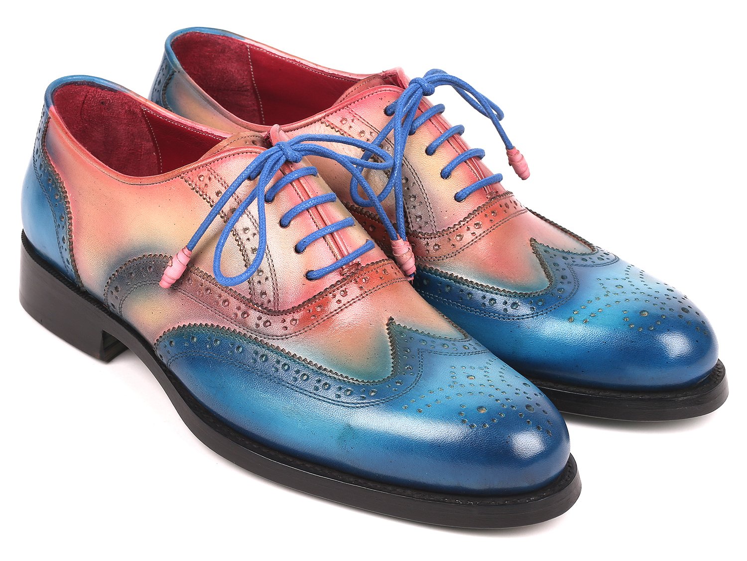 A pair of Paul Parkman Blue & Pink Wingtip Oxfords, model 027-BLUPNK, featuring intricate perforations and blue laces, is elegantly displayed with one shoe atop the other against a white background. These handmade Paul Parkman shoes boast Goodyear welted construction, ensuring both style and durability.