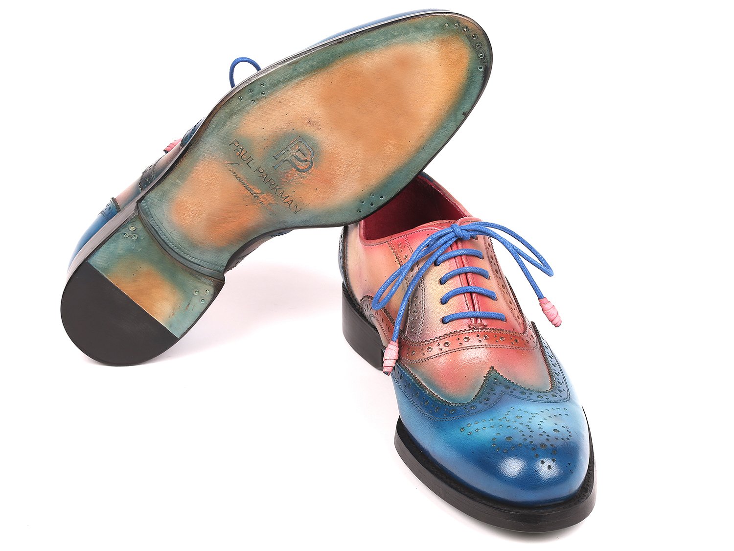 A pair of Paul Parkman Blue & Pink Wingtip Oxfords, model 027-BLUPNK, featuring intricate perforations and blue laces, is elegantly displayed with one shoe atop the other against a white background. These handmade Paul Parkman shoes boast Goodyear welted construction, ensuring both style and durability.