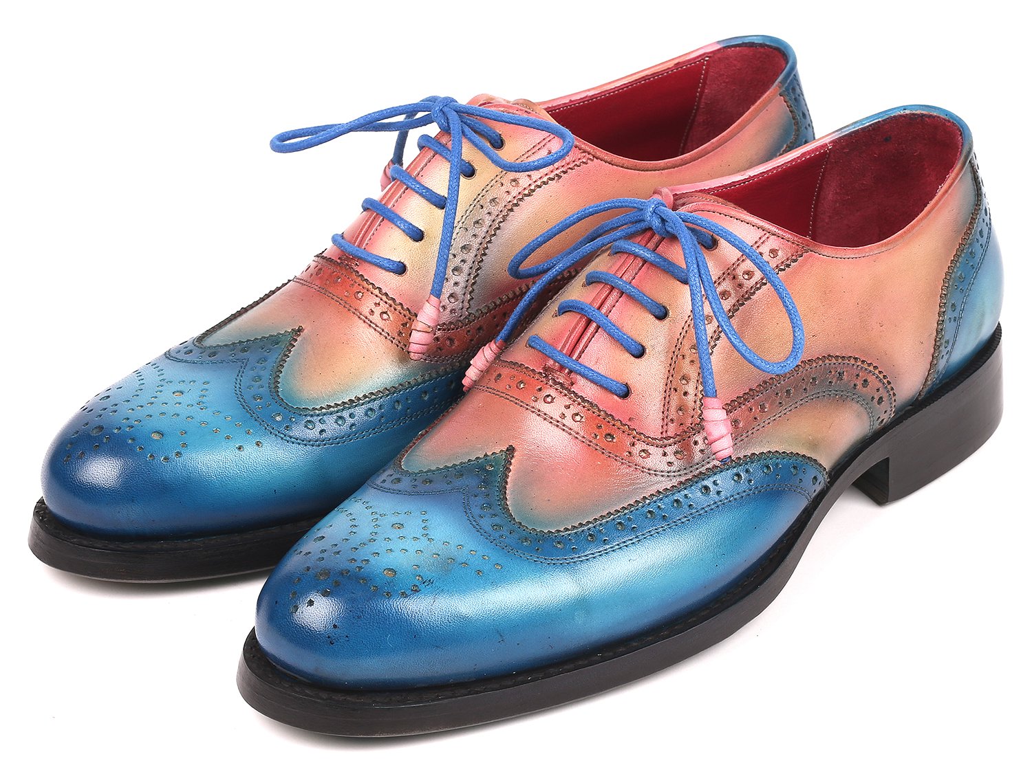 A pair of Paul Parkman Blue & Pink Wingtip Oxfords, model 027-BLUPNK, featuring intricate perforations and blue laces, is elegantly displayed with one shoe atop the other against a white background. These handmade Paul Parkman shoes boast Goodyear welted construction, ensuring both style and durability.