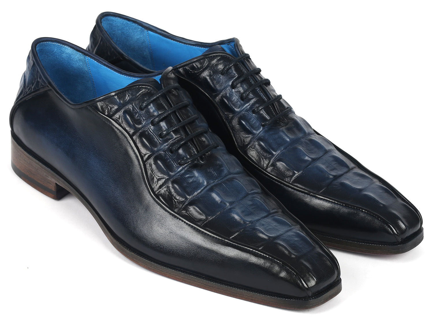 A pair of Paul Parkman Navy Croco Textured Leather Bicycle Toe Oxfords, featuring elegant blue interiors and brown soles, styled with one shoe slightly on top of the other.