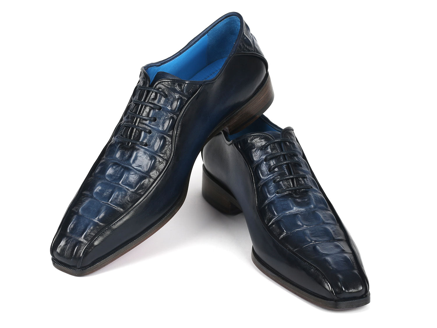 A pair of Paul Parkman Navy Croco Textured Leather Bicycle Toe Oxfords, featuring elegant blue interiors and brown soles, styled with one shoe slightly on top of the other.