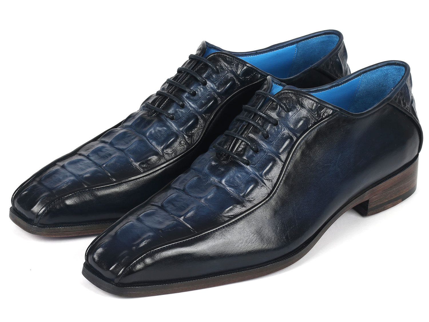 A pair of Paul Parkman Navy Croco Textured Leather Bicycle Toe Oxfords, featuring elegant blue interiors and brown soles, styled with one shoe slightly on top of the other.