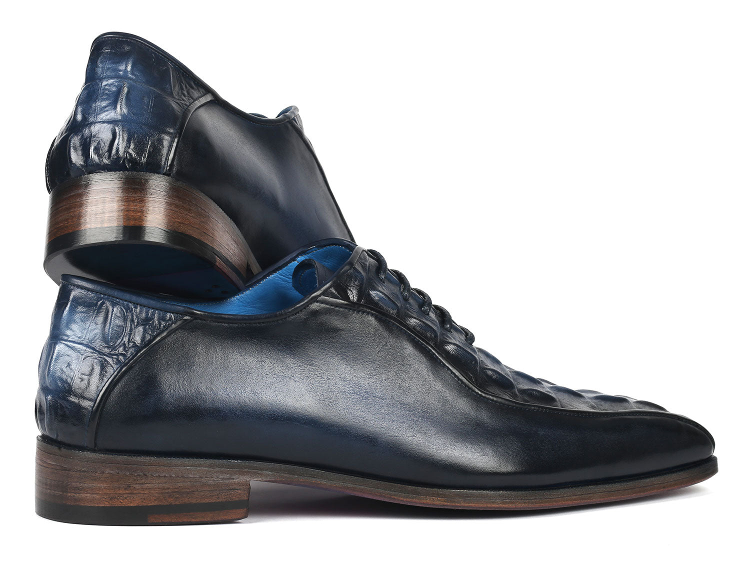 A pair of Paul Parkman Navy Croco Textured Leather Bicycle Toe Oxfords, featuring elegant blue interiors and brown soles, styled with one shoe slightly on top of the other.