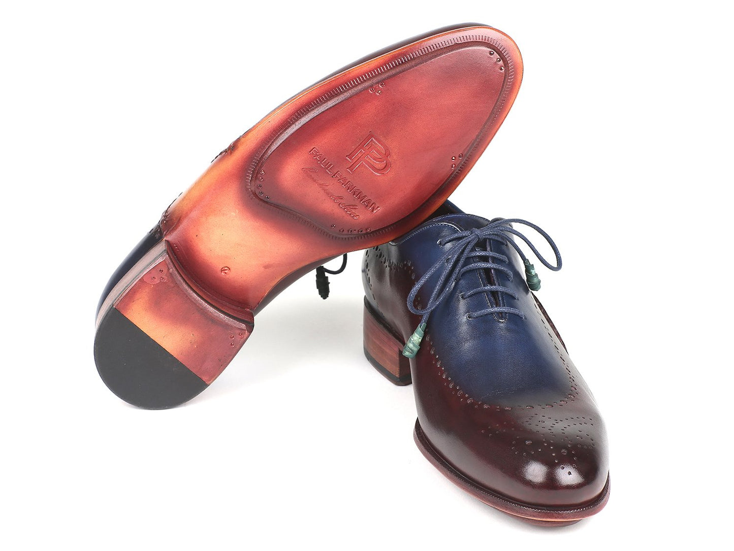 The Paul Parkman Opanka Construction Blue & Bordeaux Oxfords - 726-BLU-BRD are hand-painted leather dress shoes with decorative perforations and laces, elegantly displayed against a white backdrop. These made-to-order shoes combine style and durability through their unique Opanka construction.