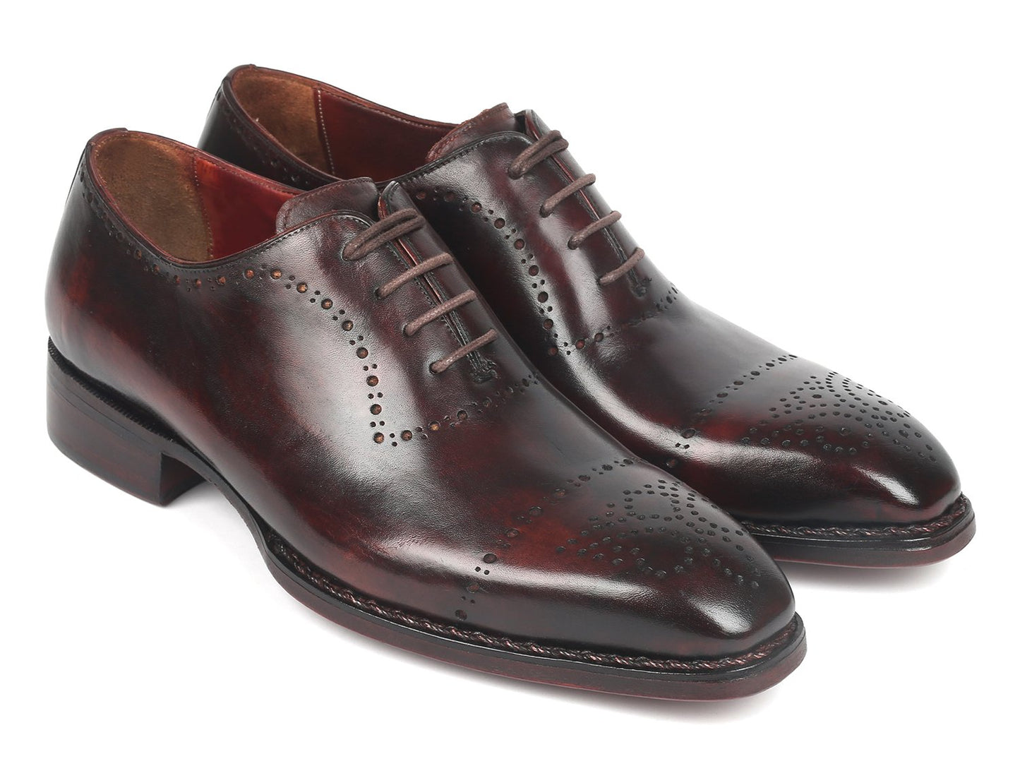 A pair of Paul Parkman Dark Bordeaux Goodyear Welted Oxfords - 56BRD83, featuring polished leather with laces and decorative perforations, is positioned with one shoe slightly raised and overlapped.