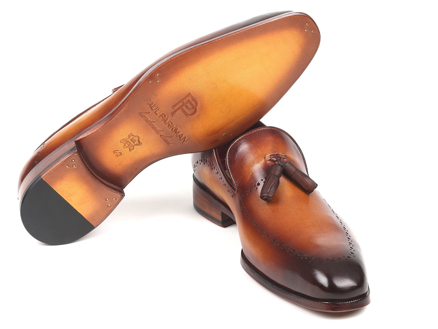 The Paul Parkman Tassel Loafer Brown - 66T81-BRW showcases hand-painted finesse and decorative perforations arranged in a crossed position on a pristine white background.