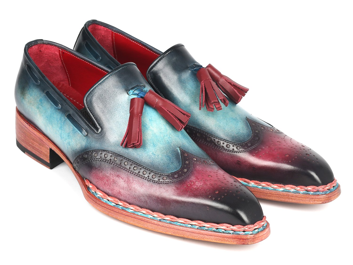 The Paul Parkman Norwegian Welted Tassel Loafers Blue & Purple - 8507-BPR feature hand-painted leather with a stunning gradient from blue to burgundy, adorned with red tassels, intricate brogue detailing, and a vibrant multicolored sole, all showcased against a plain backdrop.