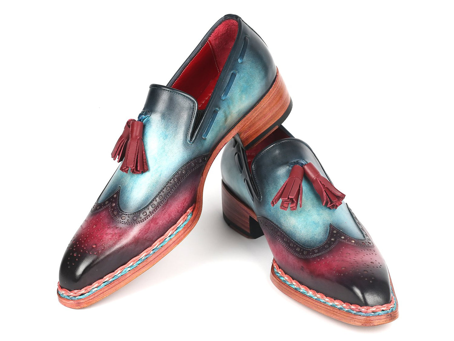 The Paul Parkman Norwegian Welted Tassel Loafers Blue & Purple - 8507-BPR feature hand-painted leather with a stunning gradient from blue to burgundy, adorned with red tassels, intricate brogue detailing, and a vibrant multicolored sole, all showcased against a plain backdrop.