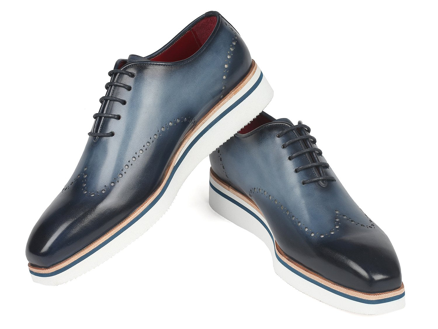 The Paul Parkman Smart Casual Wingtip Oxfords Navy - 187-NAVY are a pair of navy leather shoes with white soles, featuring decorative perforations and stitches. These stylish shoes from Paul Parkman, placed on a white background, embody style and versatility, making them perfect for any occasion.