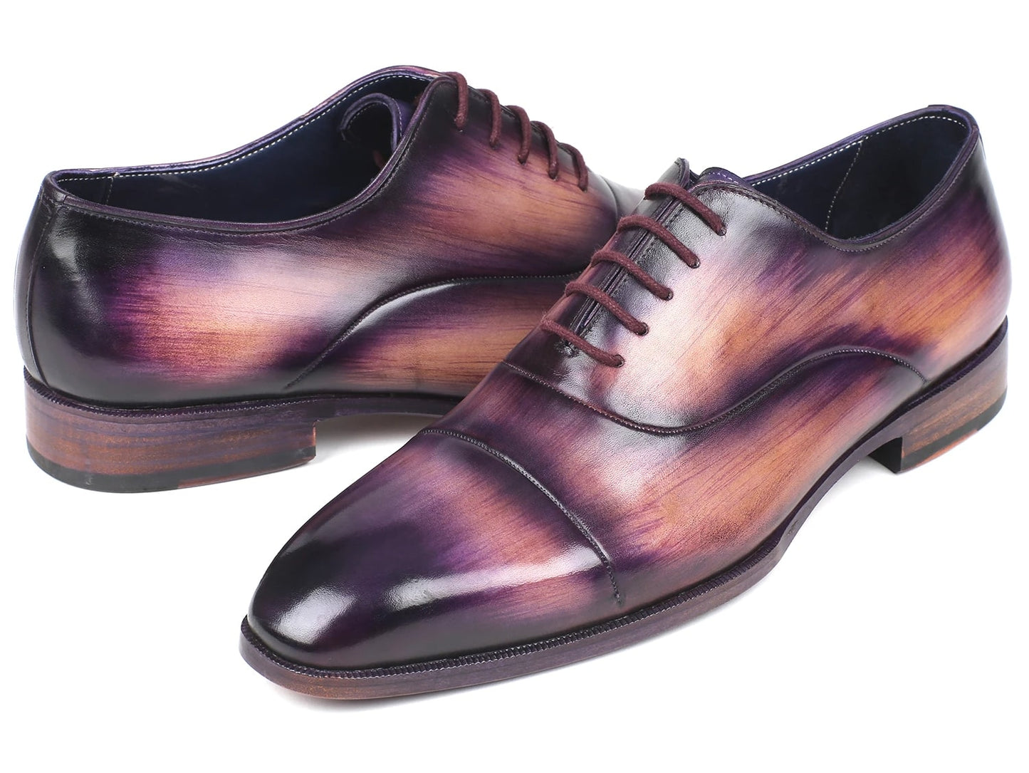 A pair of Paul Parkman Captoe Oxfords, model 1744-PRP, featuring a glossy multicolored finish that transitions from purple to pink on hand-painted leather, are laced up with one shoe slightly positioned atop the other.