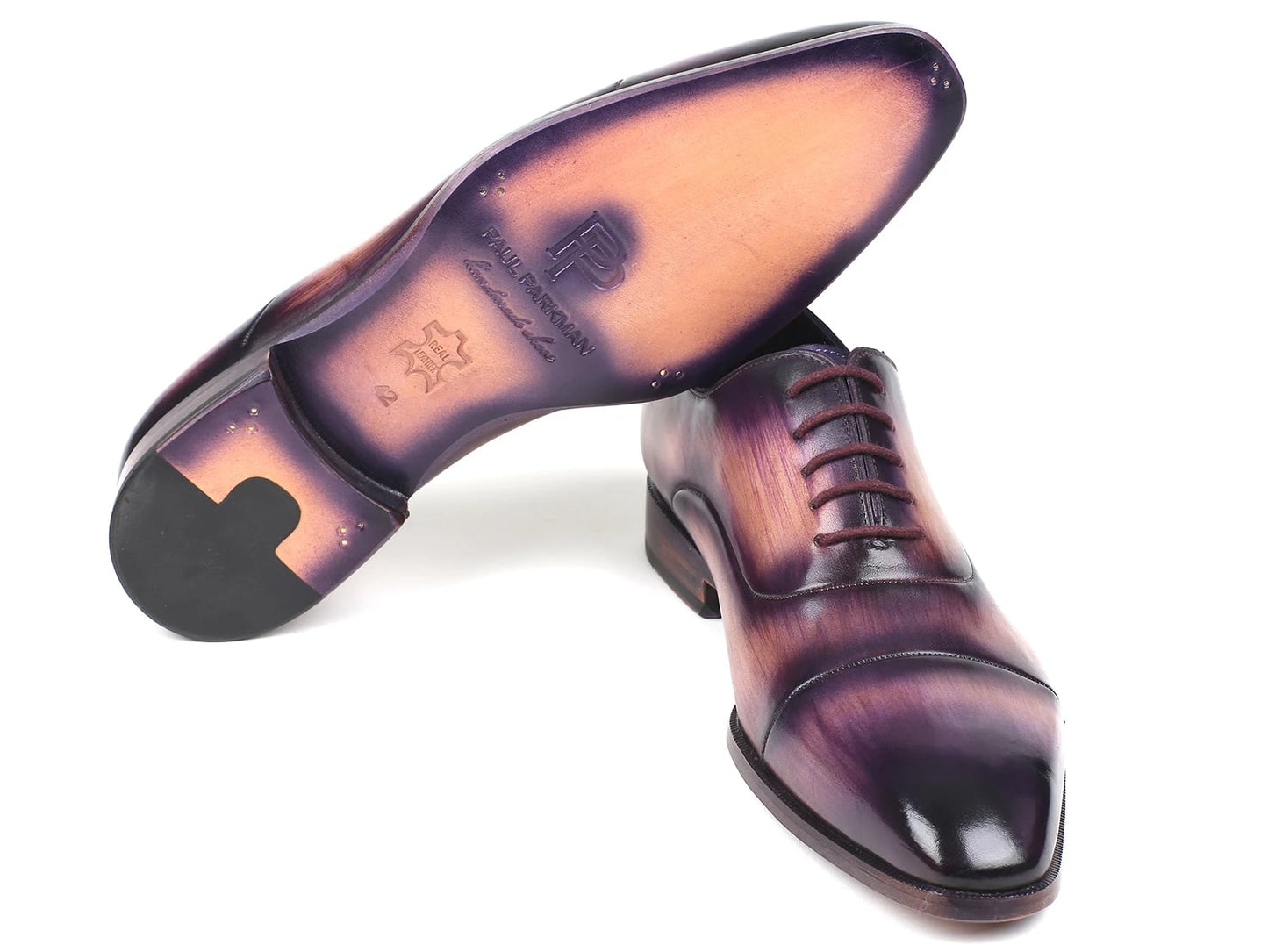 A pair of Paul Parkman Captoe Oxfords, model 1744-PRP, featuring a glossy multicolored finish that transitions from purple to pink on hand-painted leather, are laced up with one shoe slightly positioned atop the other.