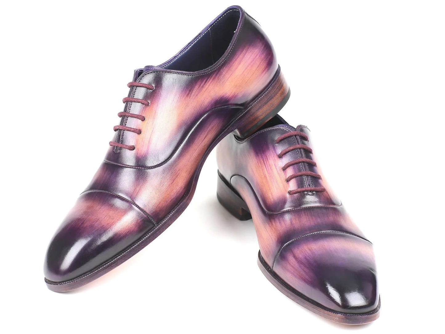 A pair of Paul Parkman Captoe Oxfords, model 1744-PRP, featuring a glossy multicolored finish that transitions from purple to pink on hand-painted leather, are laced up with one shoe slightly positioned atop the other.