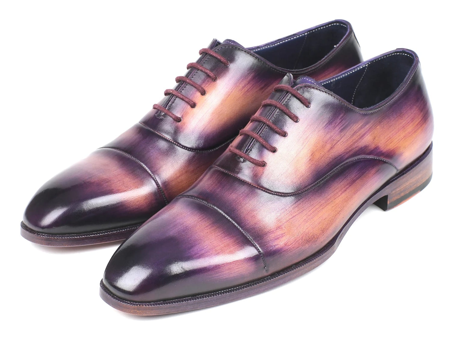 A pair of Paul Parkman Captoe Oxfords, model 1744-PRP, featuring a glossy multicolored finish that transitions from purple to pink on hand-painted leather, are laced up with one shoe slightly positioned atop the other.