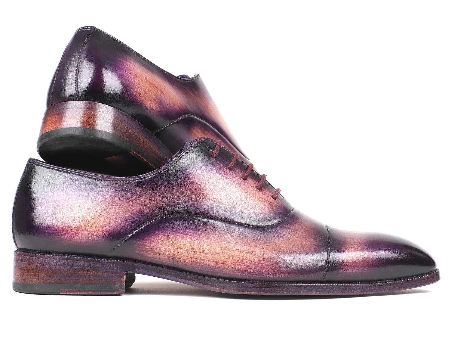 A pair of Paul Parkman Captoe Oxfords, model 1744-PRP, featuring a glossy multicolored finish that transitions from purple to pink on hand-painted leather, are laced up with one shoe slightly positioned atop the other.