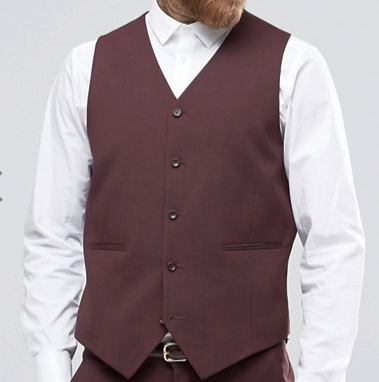 A man dressed in the Vinci Slim Fit Single Breasted 5 Button Vest (Burgundy) OV-900 from Vinci Suits, layered over a crisp white shirt, stands confidently against a light gray background with his beard neatly trimmed.