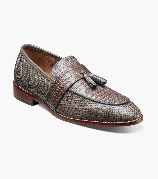 Gray tassel loafer designed by Stacy Adams, made from lizard print leather with dark brown trim and a low heel. It includes a Memory Foam insole for enhanced comfort and is displayed against a plain background.