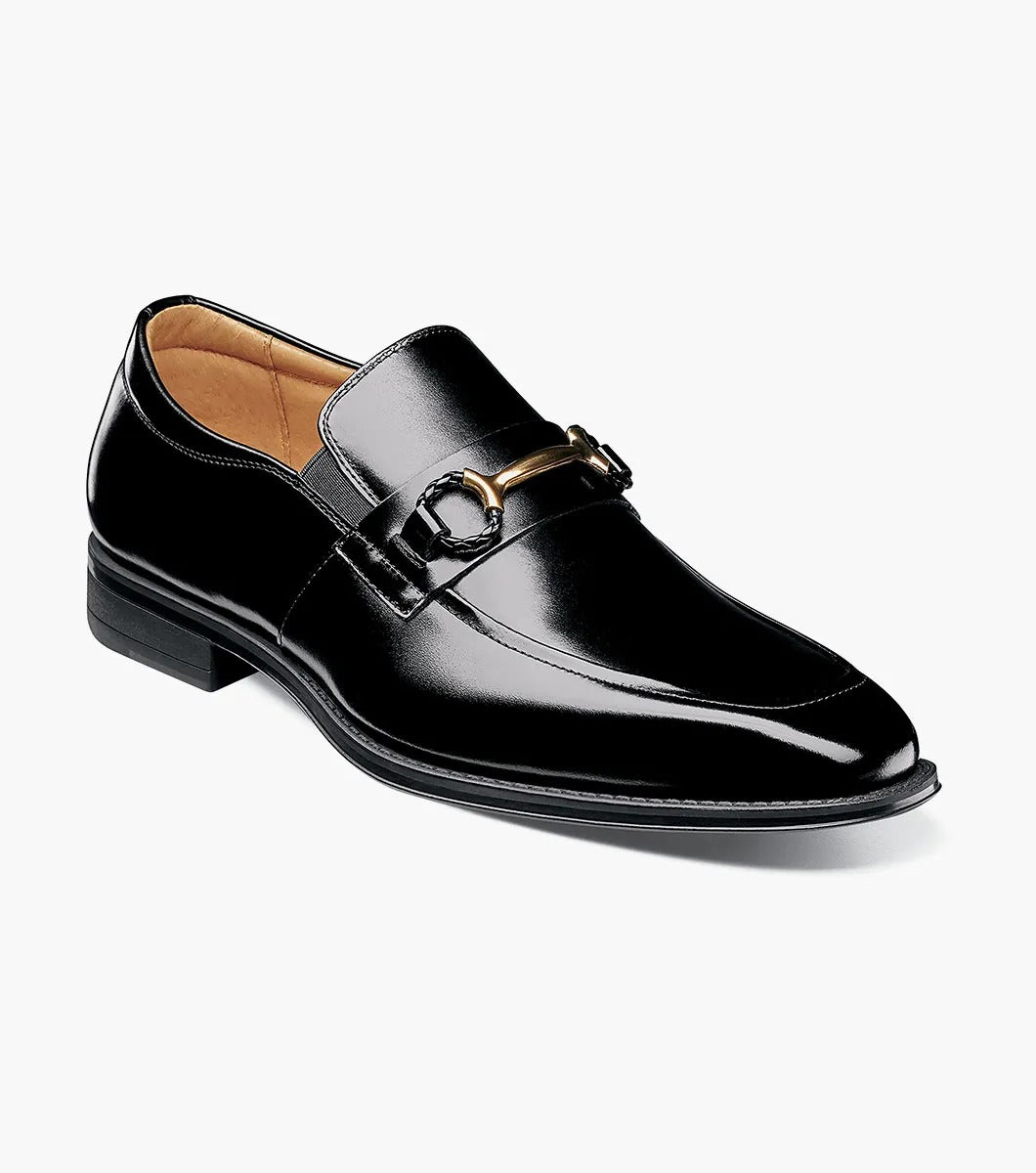 The Stacy Adams PIERCE Moc Toe Bit Slip On in black, style number 25245-001, features a metallic buckle detail and a low heel. It comes with a comfortable Memory Foam insole and is displayed against a white background.