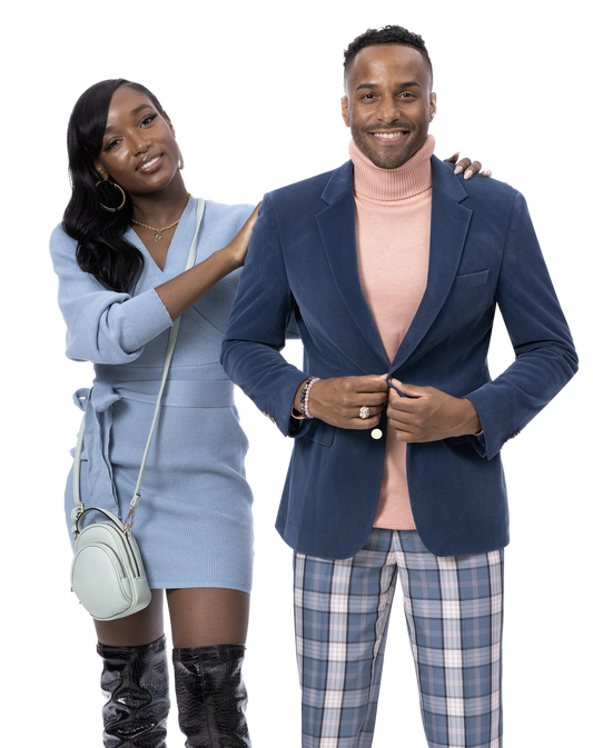 A woman in a light blue dress stands beside a man dressed in a modern fit, featuring an EJ Samuel Steel Blue Blazer and EJ Samuel Steel Blue Plaid Pants PL101. She has one hand on his shoulder, both smiling warmly.