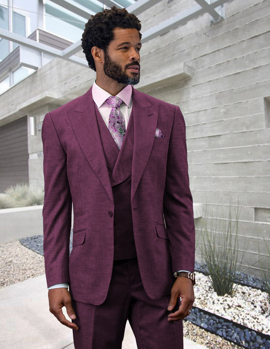 A man in a STATEMENT CLOTHING | RIMA-MAUVE suit by Statement Clothing, complete with a purple double-breasted vest and peak lapel, paired with a pink shirt and patterned tie, stands confidently in front of a modern building.