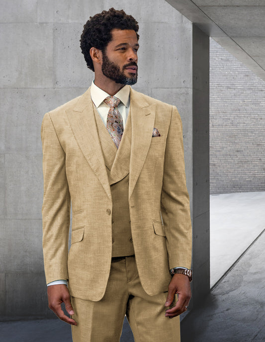 A person wearing the STATEMENT CLOTHING | RIMA-TAN suit from Statement Clothing, featuring a patterned tie and peak lapel, stands in a concrete hallway, looking to the left.