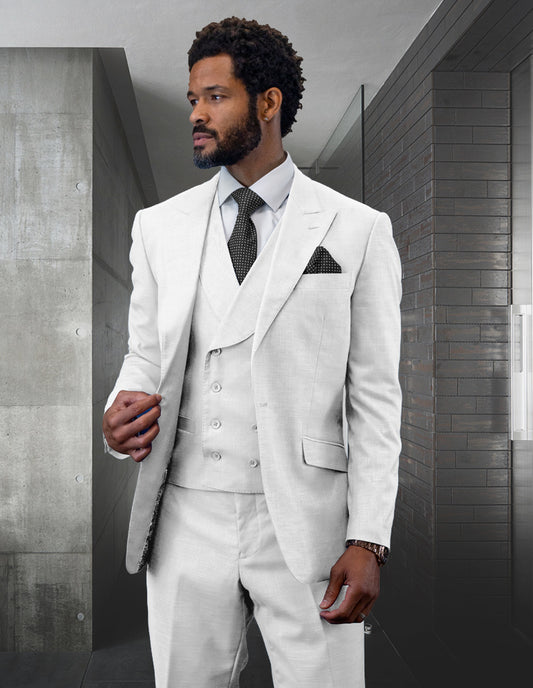 A man dressed in Statement Clothing's light gray wool suit, featuring the RIMA-WHITE double-breasted vest, stands in a modern room with gray walls.